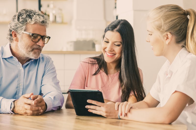 female-agent-manager-meeting-with-couple-young-mature-customers-presenting-content-tablet.jpg